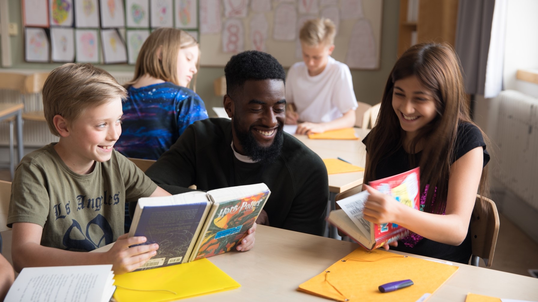 Lärare och två glada elever i ett klassrum